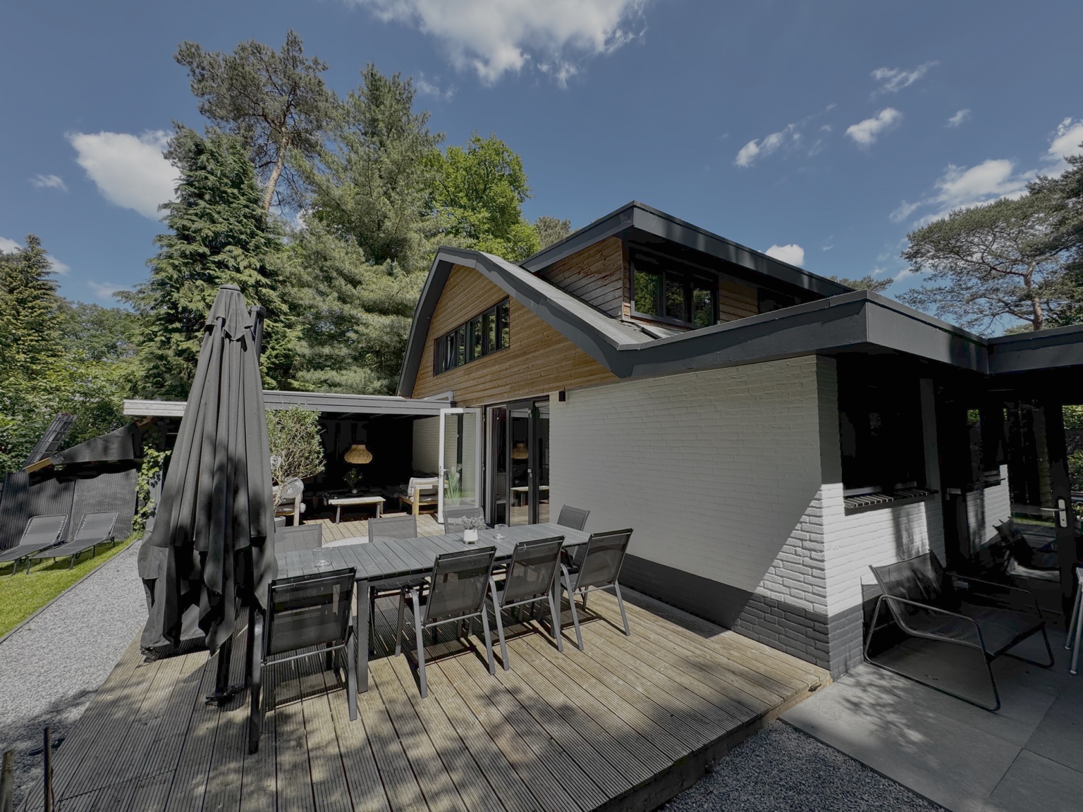 Voorkant van de villa met houten gevel en groen eromheen